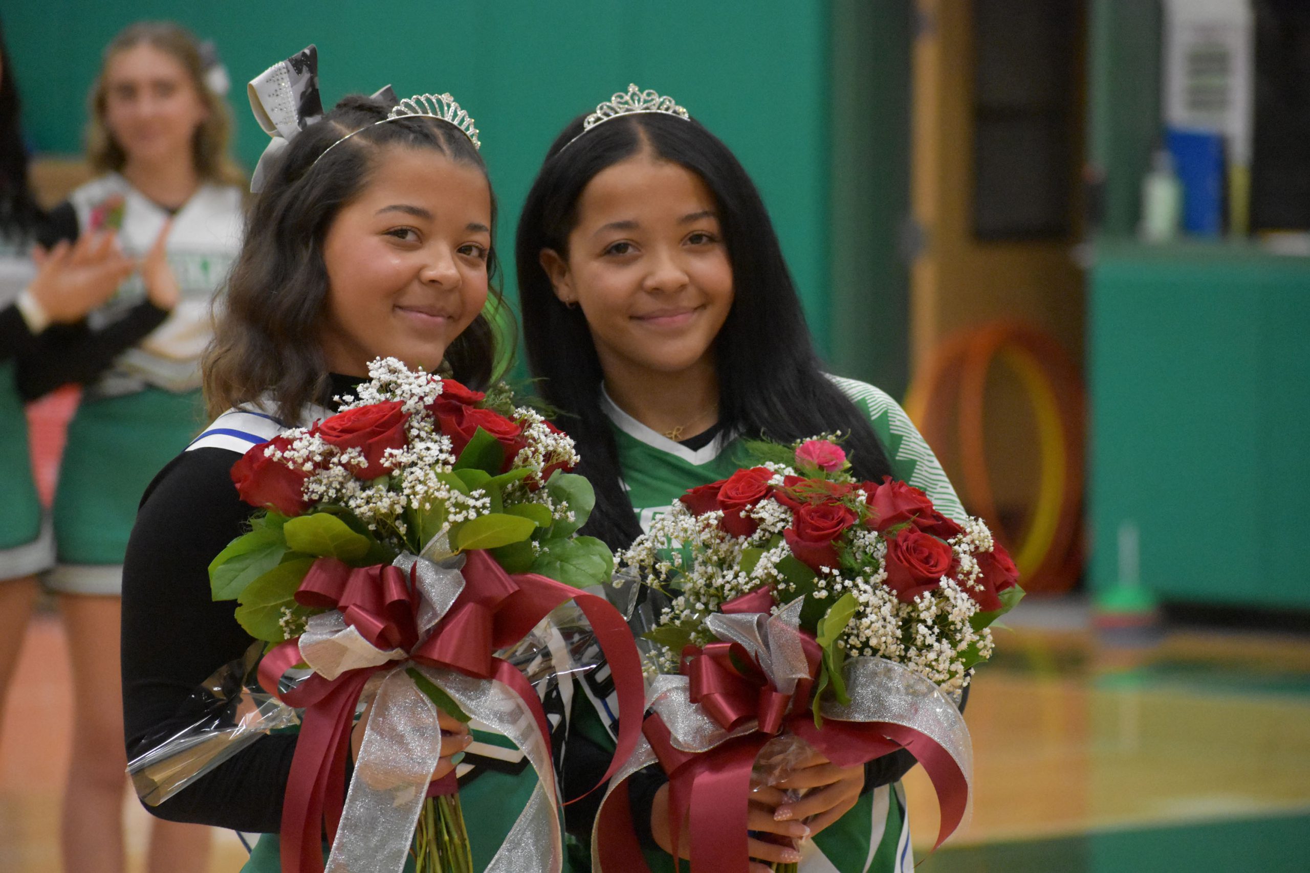 Twins posing with flowers and crowns after being named homecoming queens
