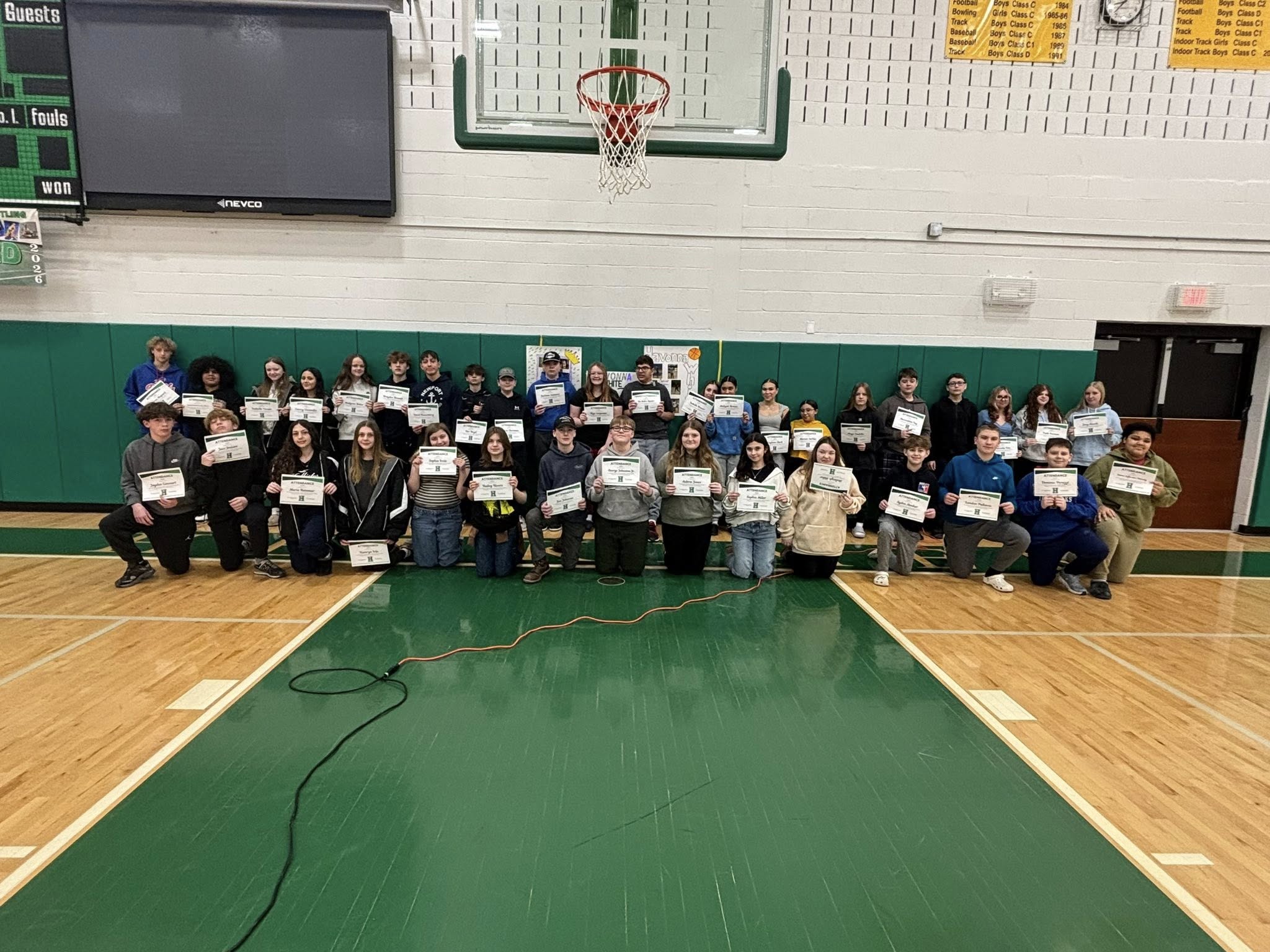 Large group of students posing with attendance certificates in gym