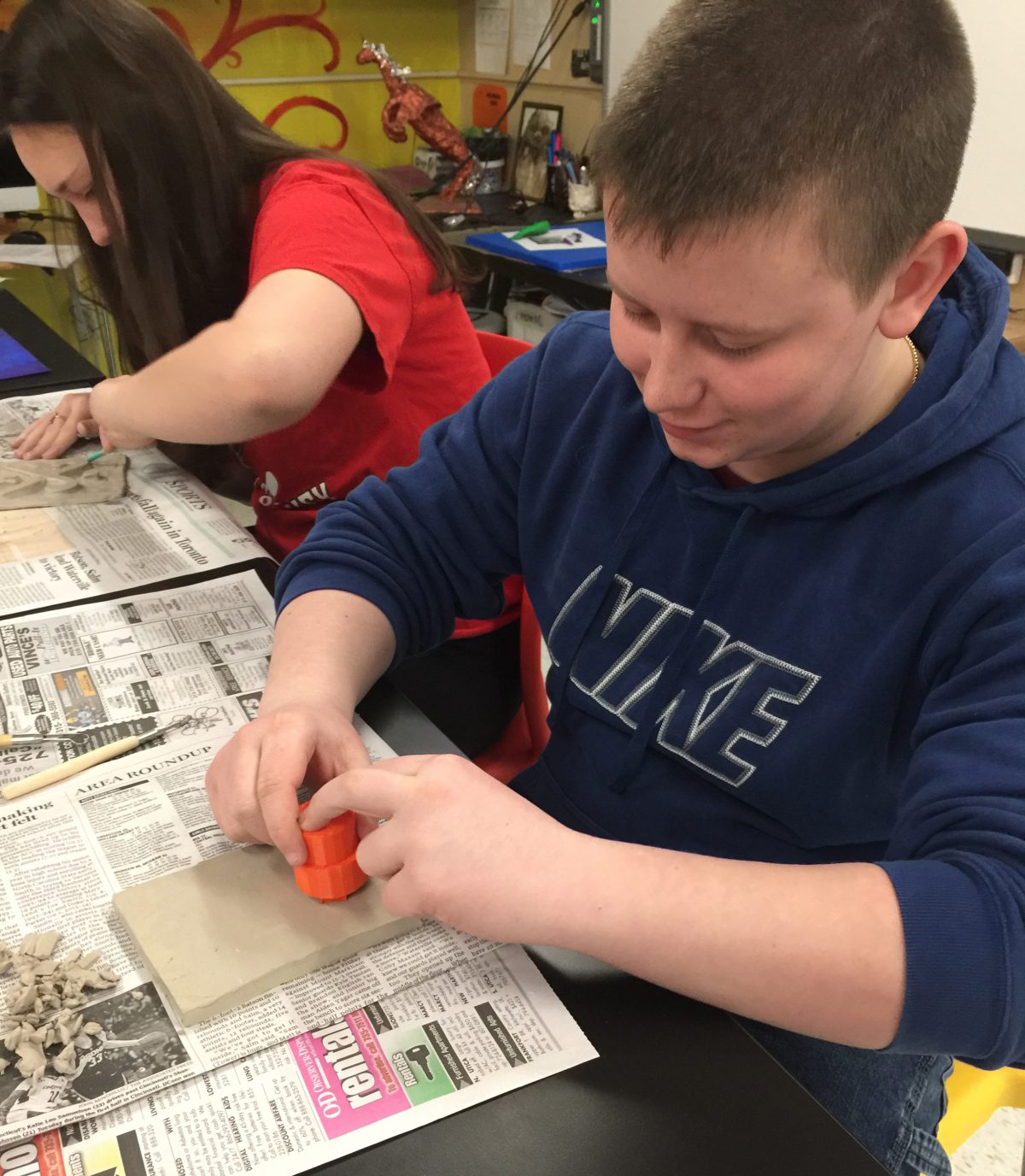 Students press stamps into clay slabs