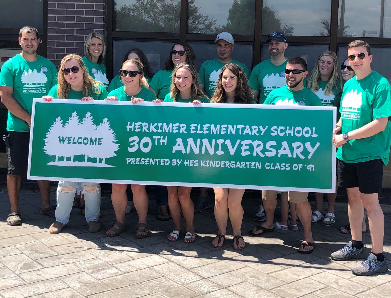 people hold a banner celebrating the 30th anniversary of the elementary