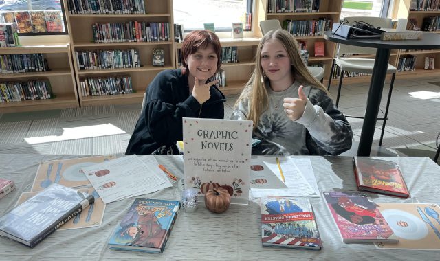 Students posing with books in the library