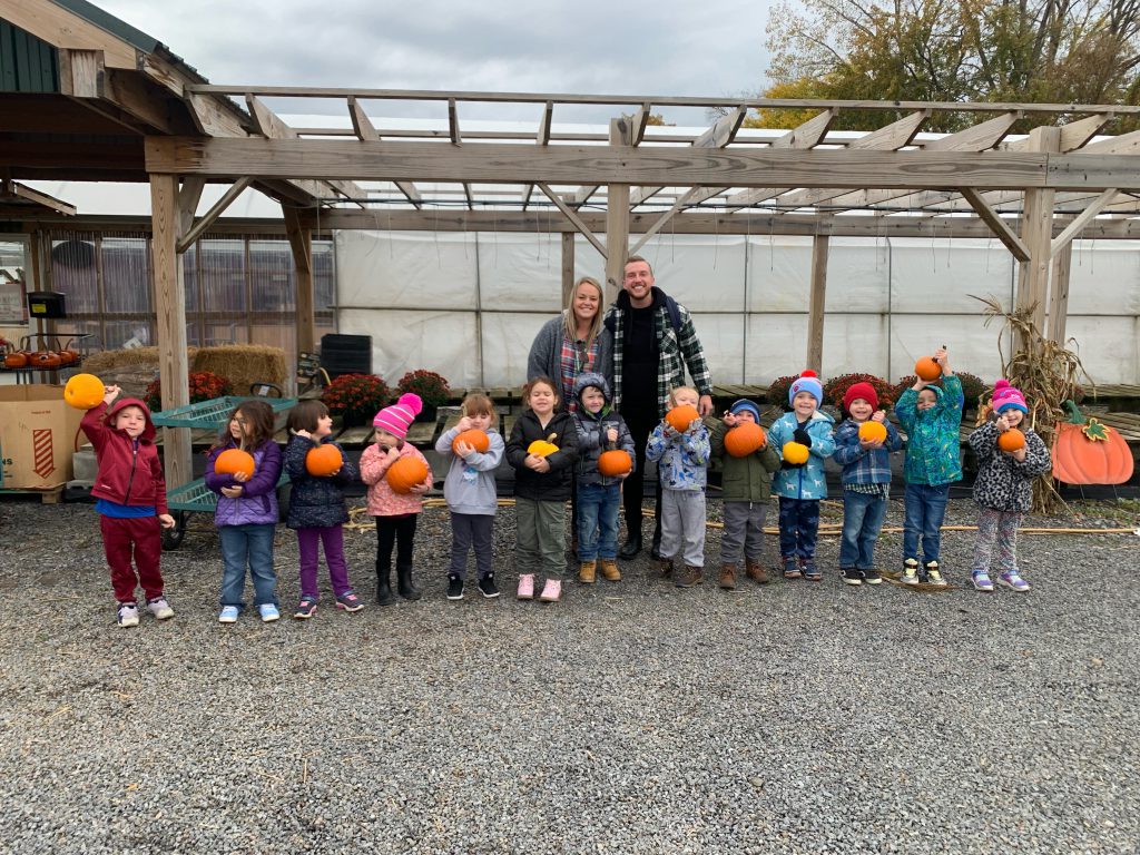 PreK students posing in a row with pumpkins at Annutto's
