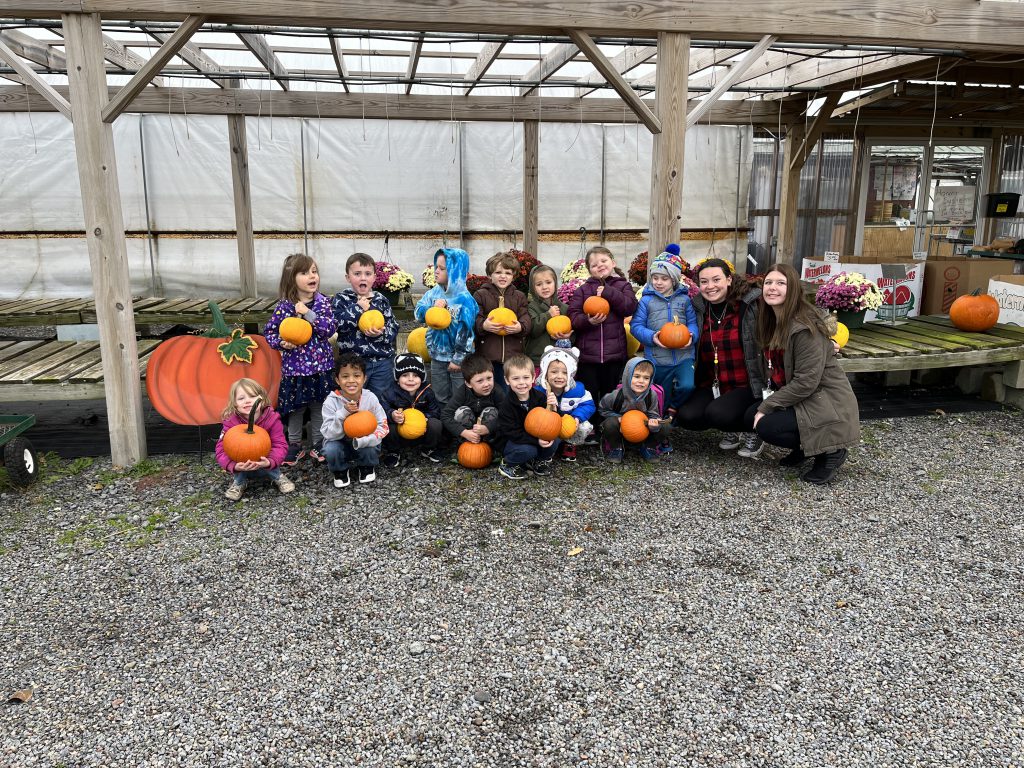PreK students posing in two rows with pumpkins at Annutto's