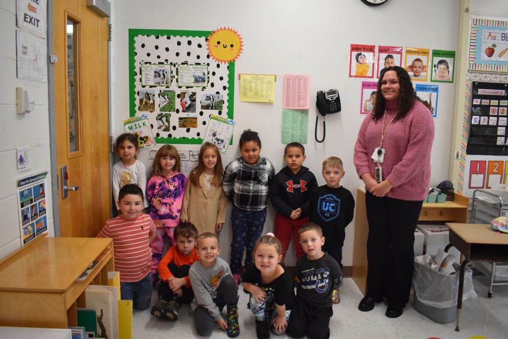 Amanda Johnson and her kindergarten class posing with photos about the cow the class adopted
