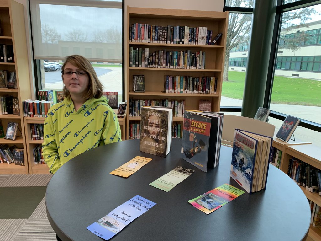 Sixth-grader Isabella Scalise posing by bookmarks in the library