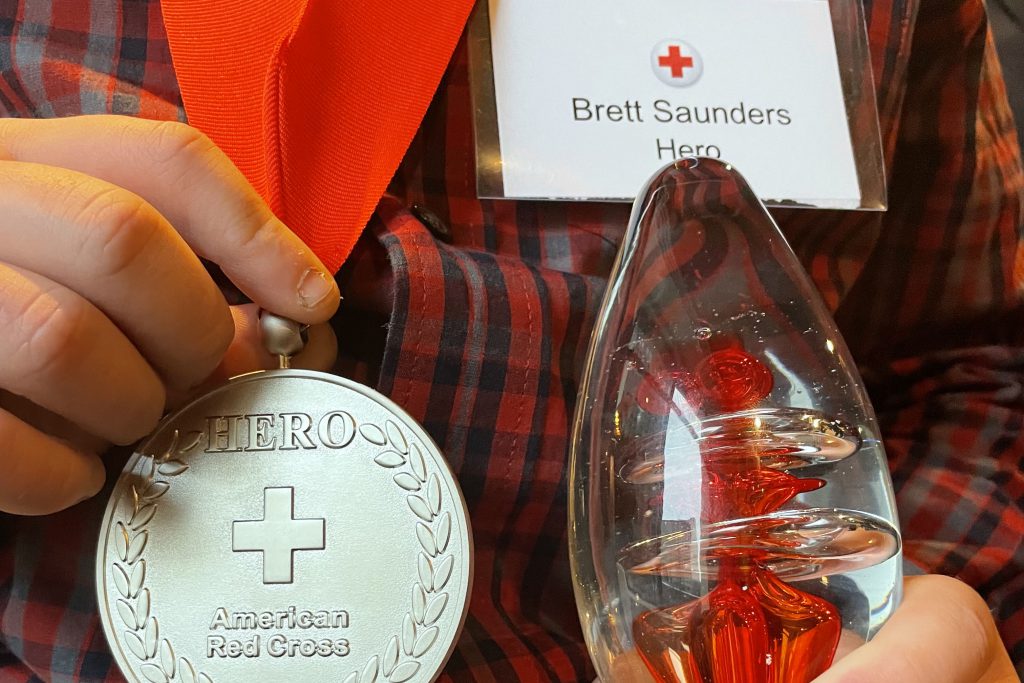 Brett Saunders' hands holding his hero award and medal