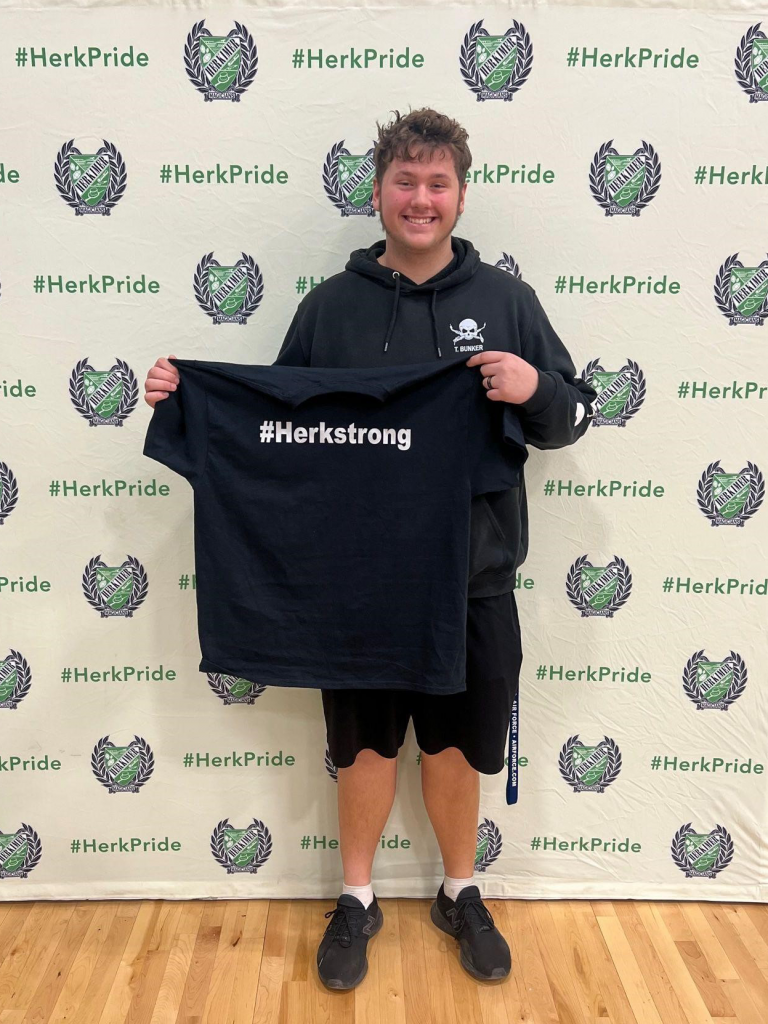 Student Trent Bunker holding up a #HerkStrong shirt received for winning a PE character recognition award