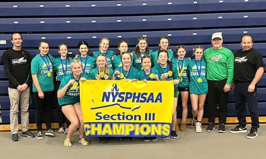 Girls indoor track team poses with sectional championship banner