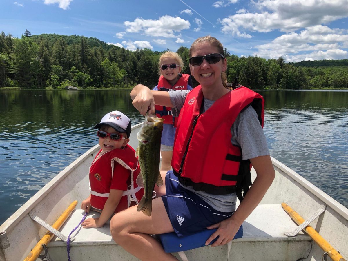 Leah Zorn holding up a fish while on a boat with two children