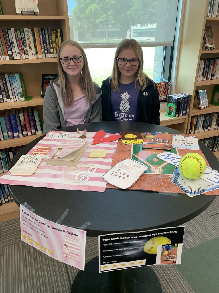 Two students posing with their Book Bentos in the library