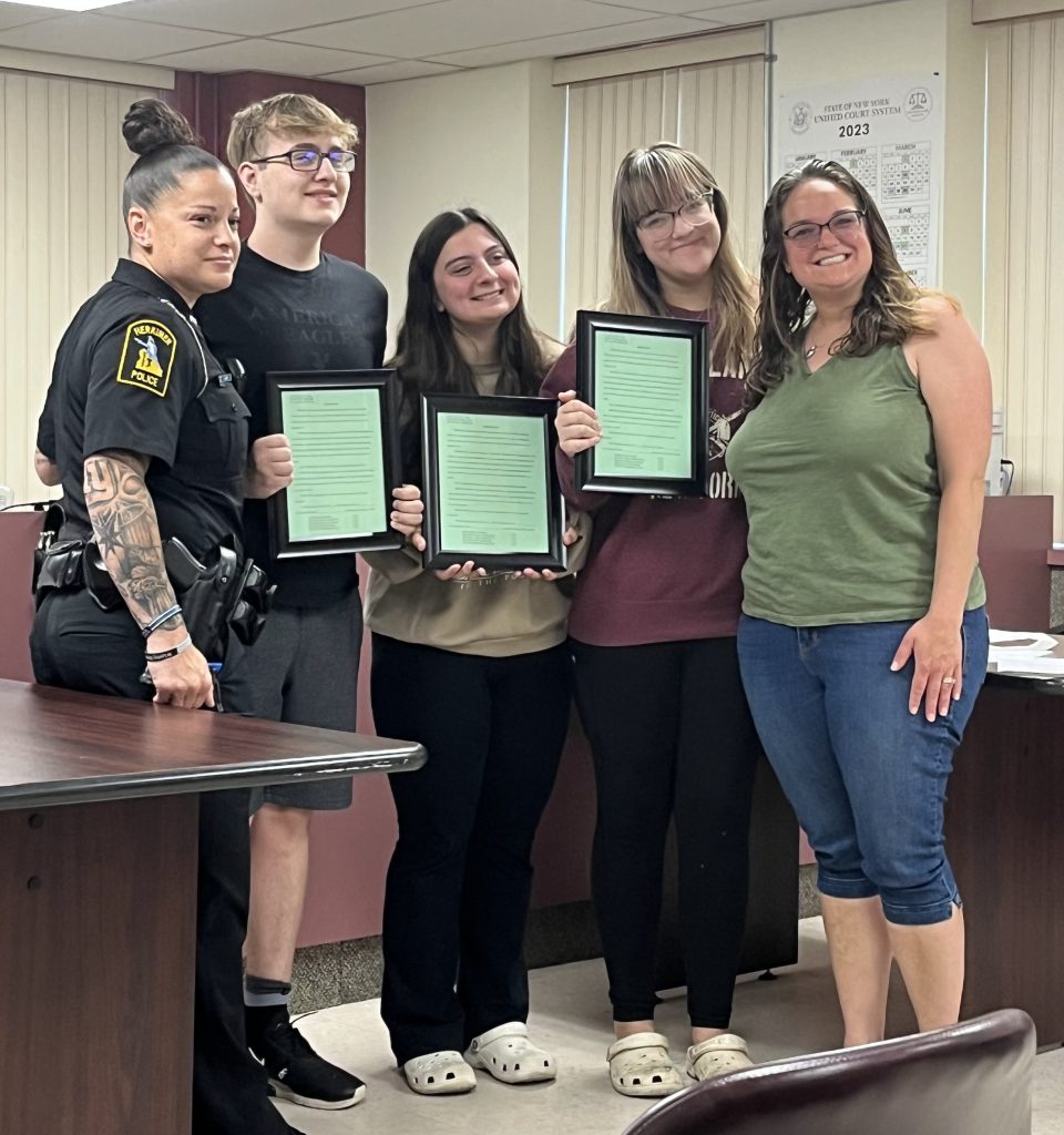 Civics students, social studies teacher and SRO pose with parking resolution copies.