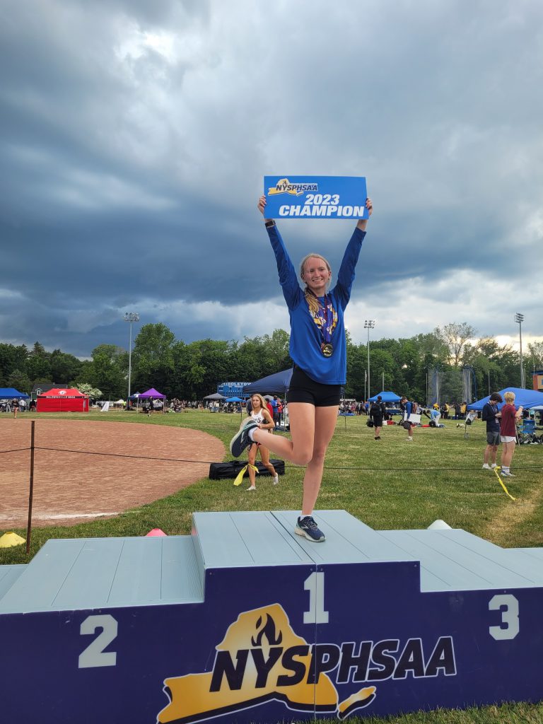 Melia Couchman holding up her 2023 state championship in pole vault sign