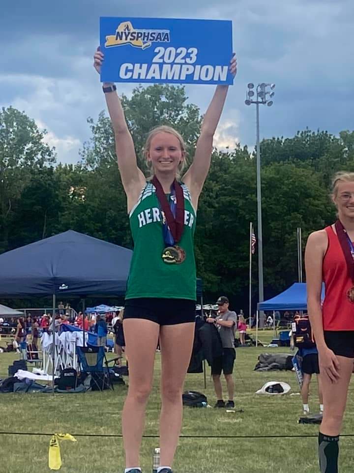 Melia Couchman holding up her 2023 state championship in pole vault sign on the medal stand
