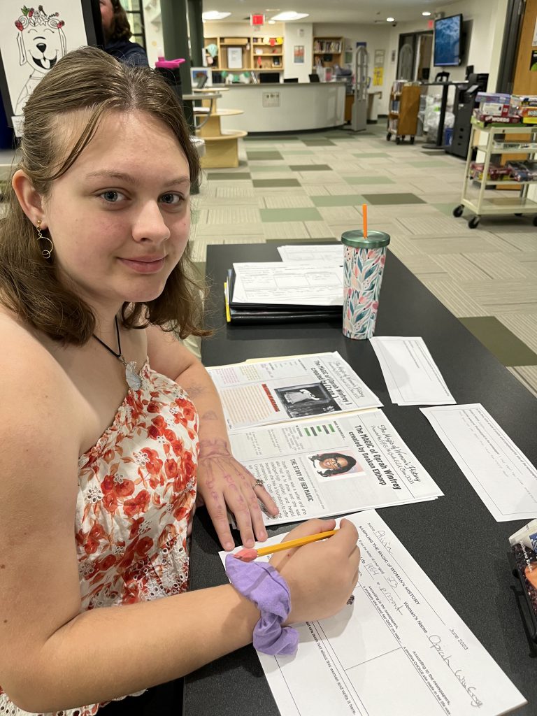 Seventh grade officer with a printed newspaper from a project about the magic of women's history