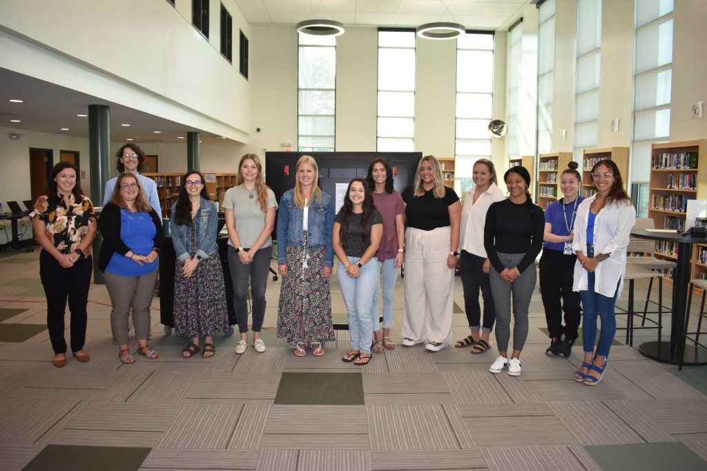 New teachers and staff pose together in the library