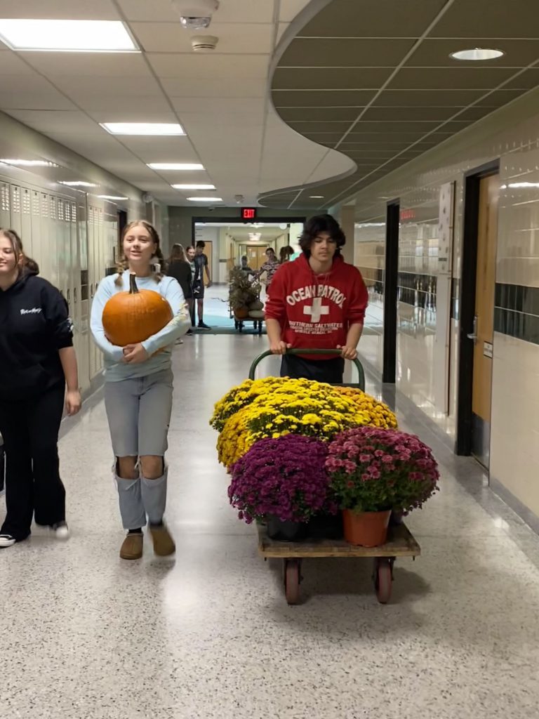 Students in high school hallway transporting materials for sign