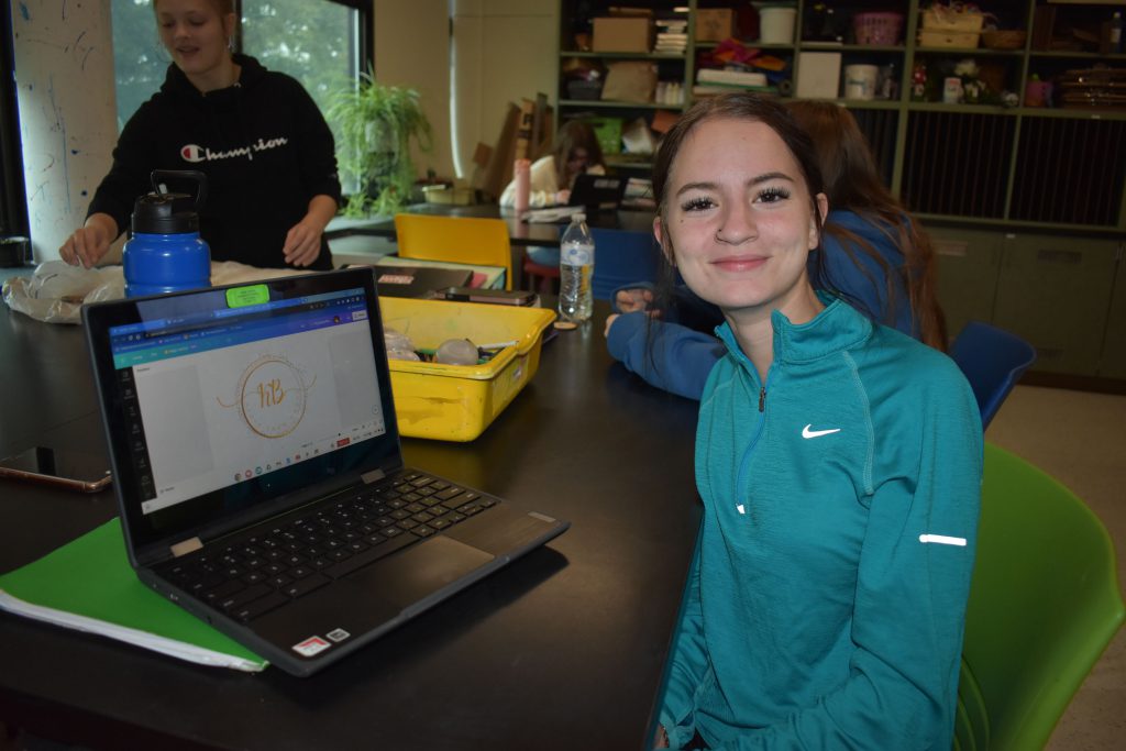 Social emotional artistic learning student next to her coin design on a computer screen