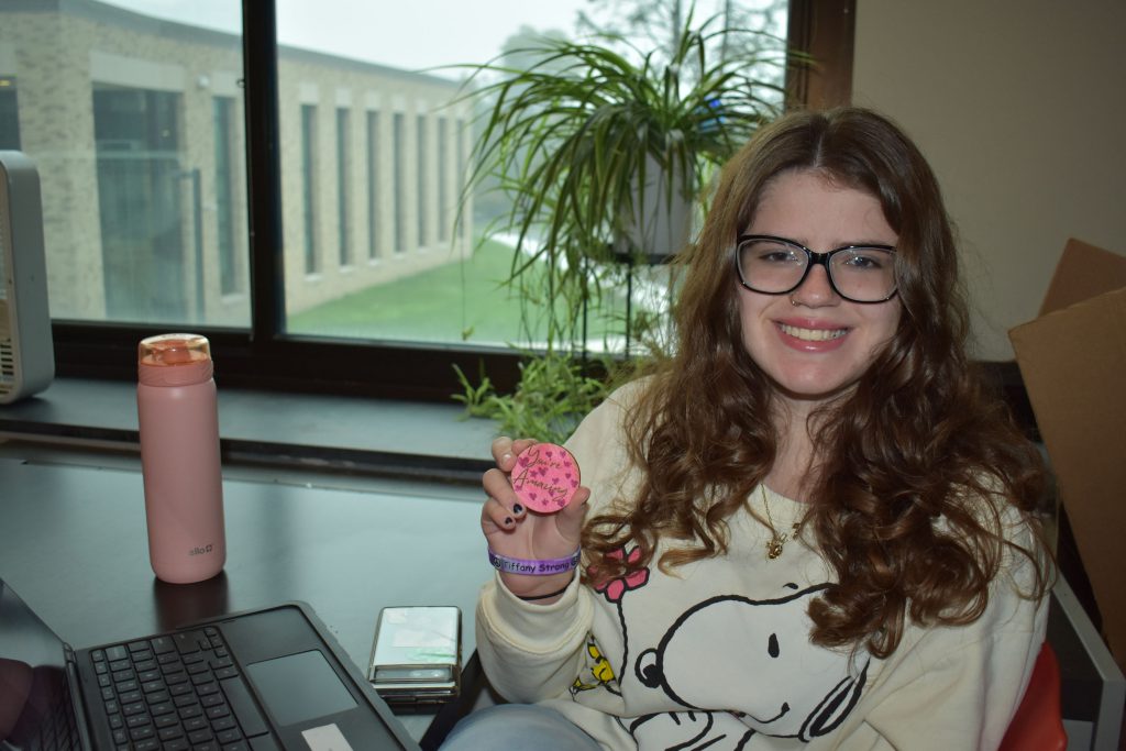 Social emotional artistic learning student holding a wood coin she designed in class