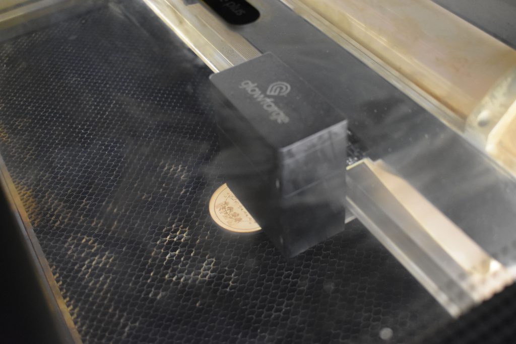 Wood coin on Glowforge being engraved