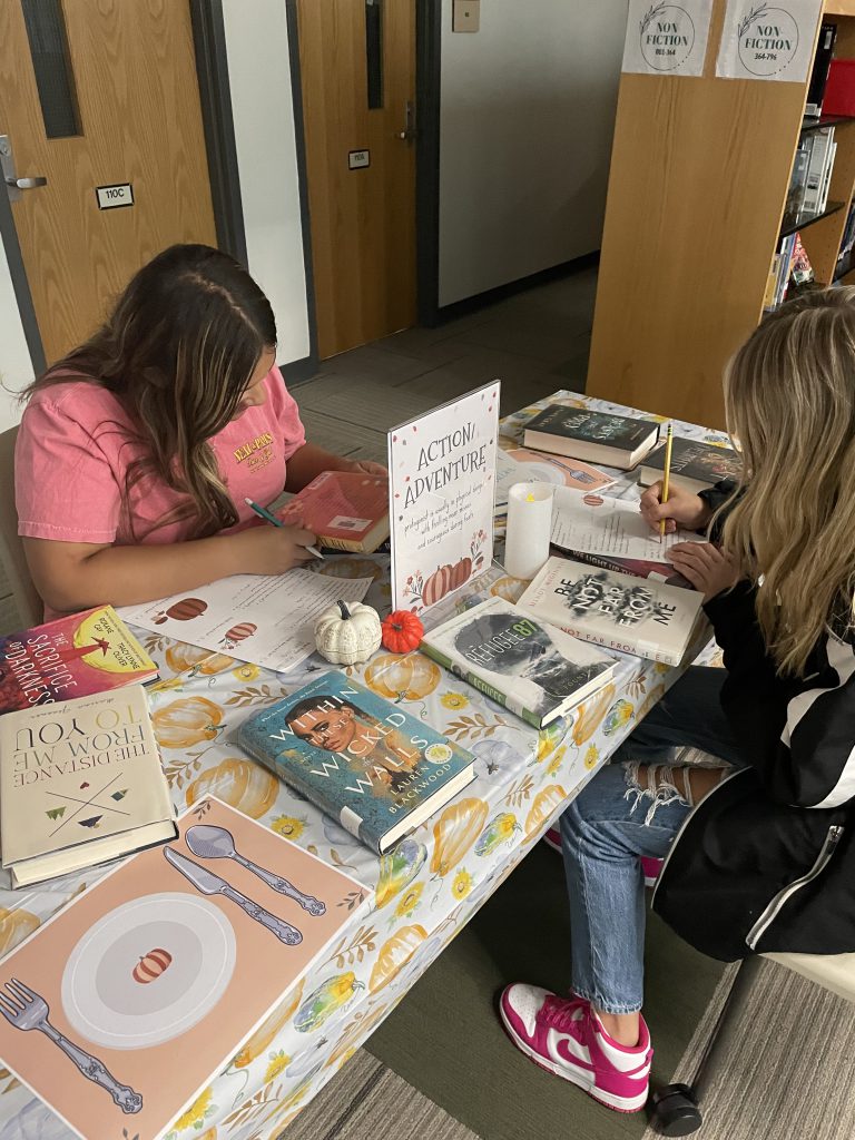Two students looking at books at book-tasting event in Library Media Center
