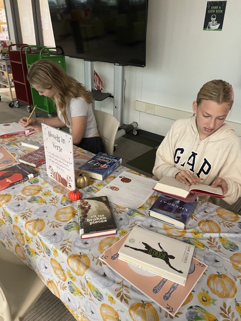 Two students looking at books at book-tasting event in Library Media Center