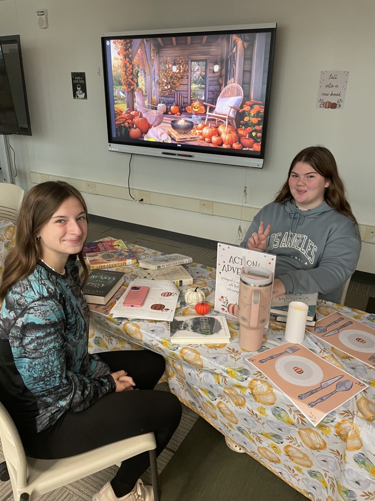 Two students looking at books at book-tasting event in Library Media Center