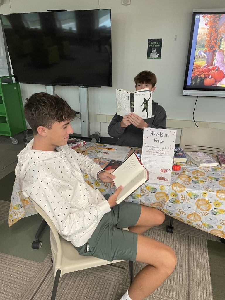 Two students looking at books at book-tasting event in Library Media Center