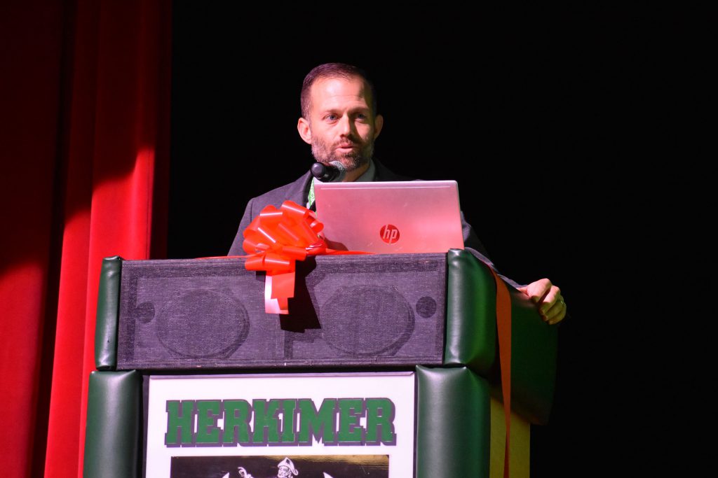 Herkimer Jr./Sr. High School Principal Zach Abbe speaks on stage at Connected Community Schools ribbon-cutting ceremony for Herkimer