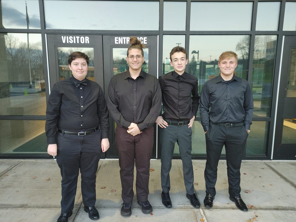 Four Herkimer students posing in front of the school