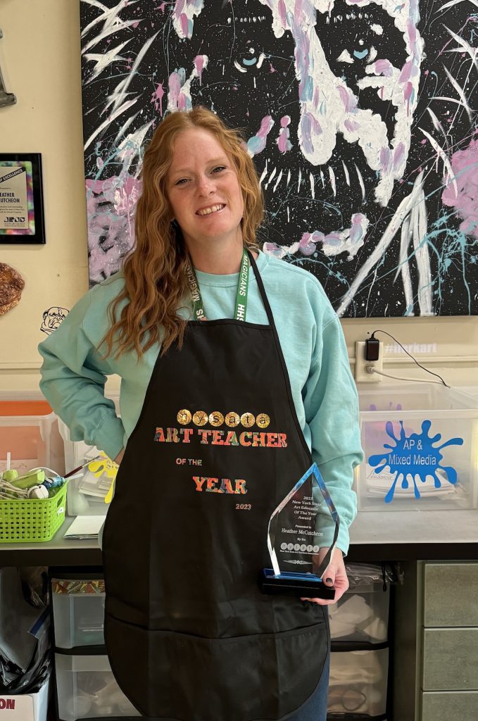 Heather McCutcheon holding Art Educator of the Year Award in classroom