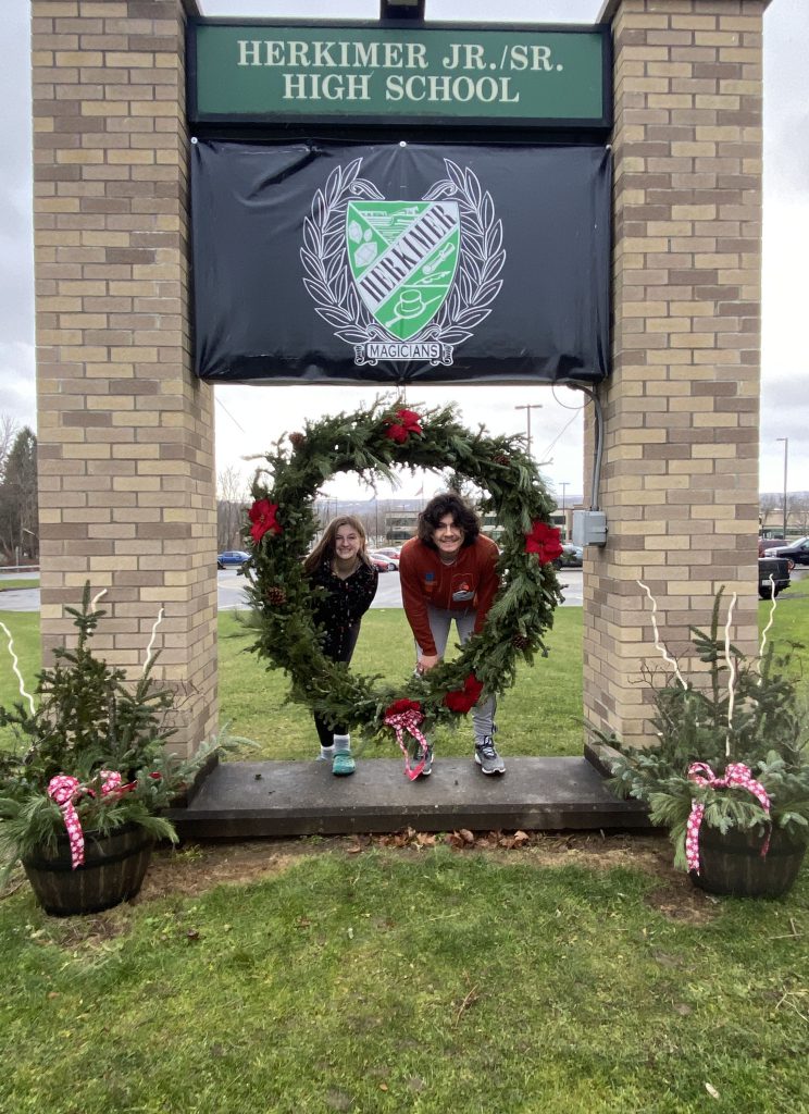 Landscape design students posing with a wreath at the high school entrance sign