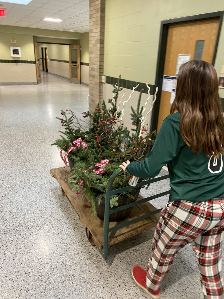 Landscape design student pushing a cart of festive displays in the hallway