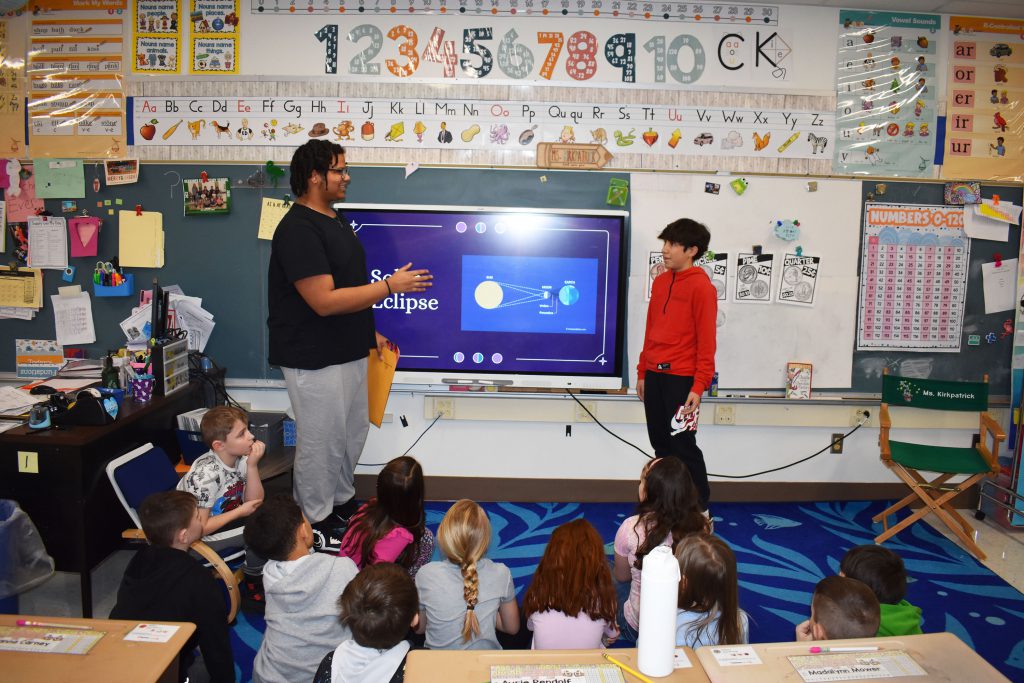 Two 10th graders presenting about the eclipse to second graders