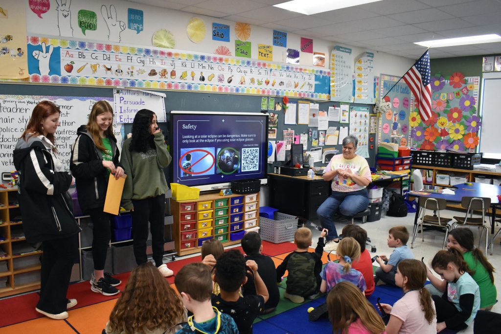 Three 10th graders presenting about the eclipse to second graders