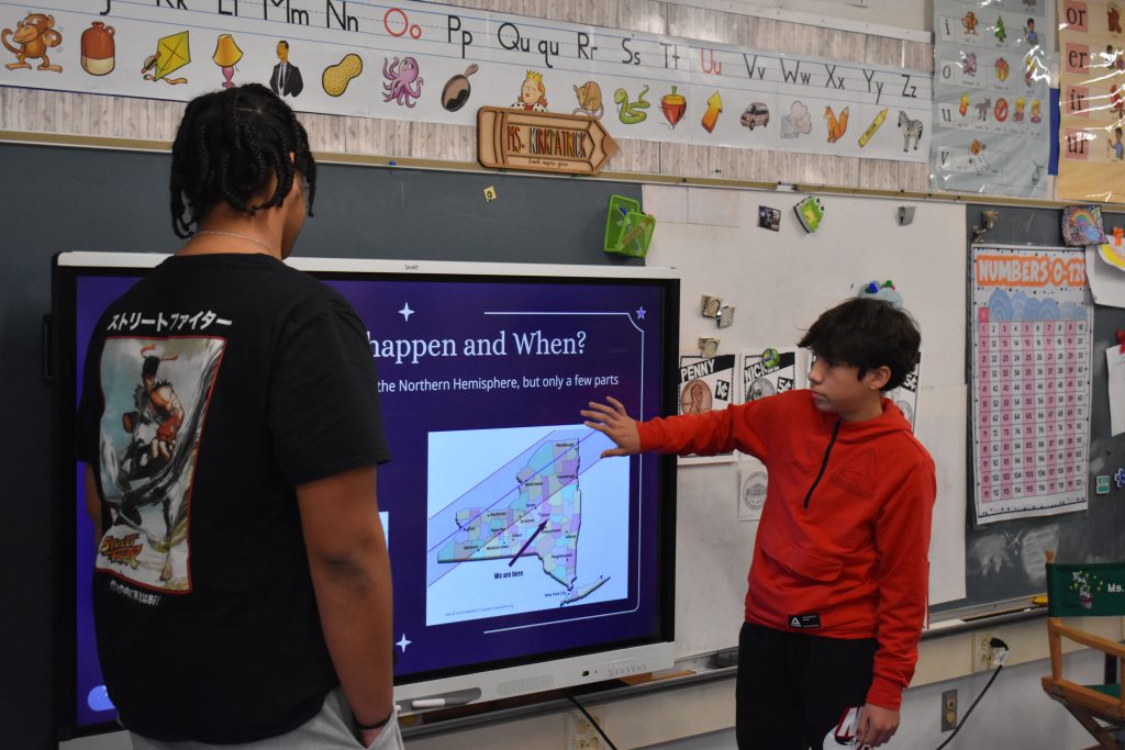 Two 10th graders presenting about the eclipse to second graders
