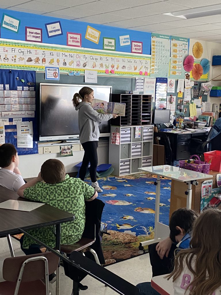 High school agriculture student reading to second graders