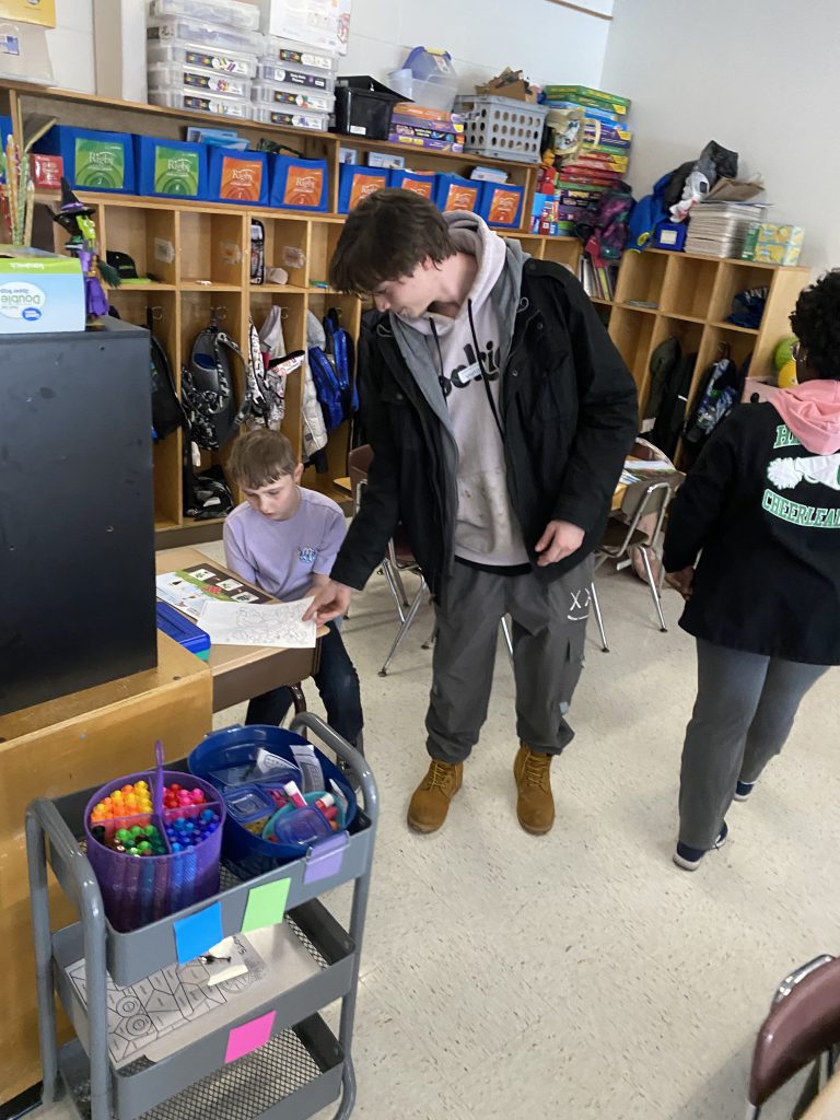 High school agriculture student helping second graders with activity