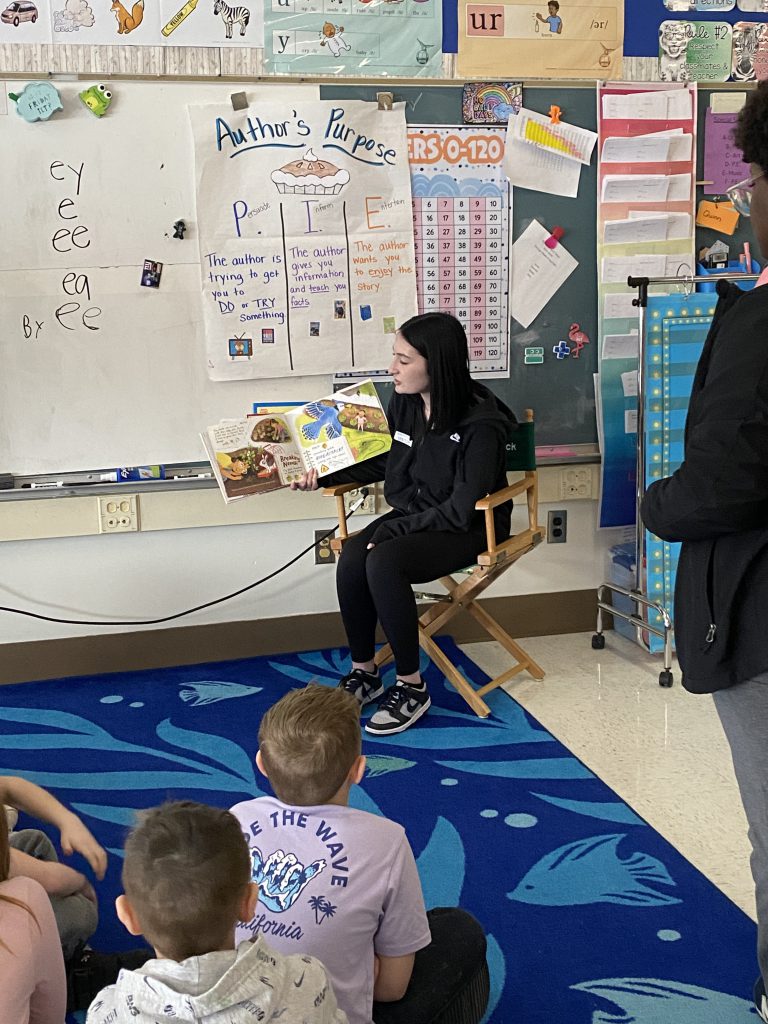 High school agriculture student reading to second graders