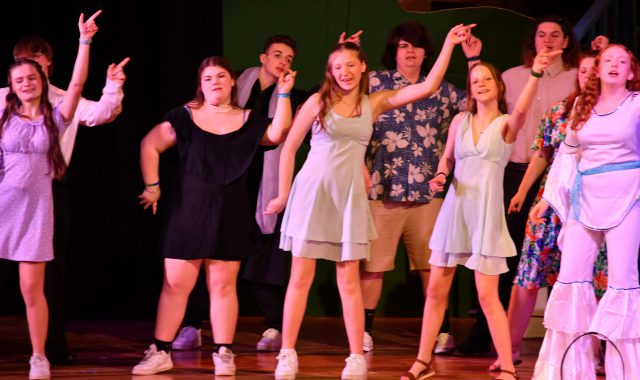 Students performing on stage for a musical