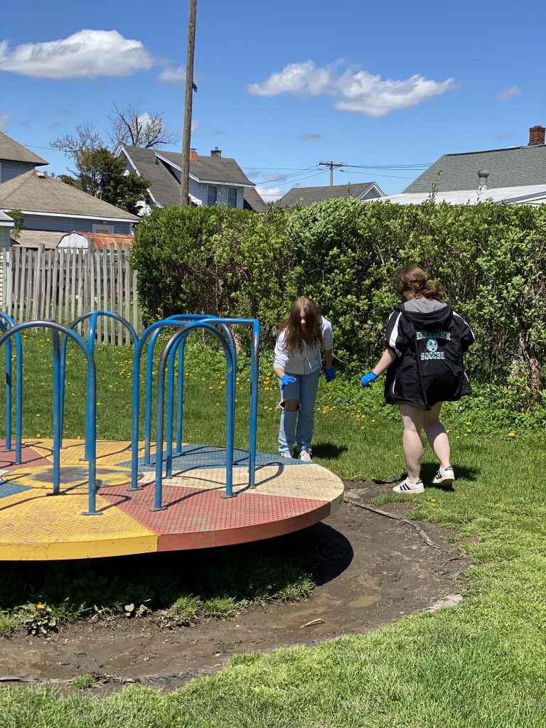 Two students cleaning up at Harmon Park by playground equipment