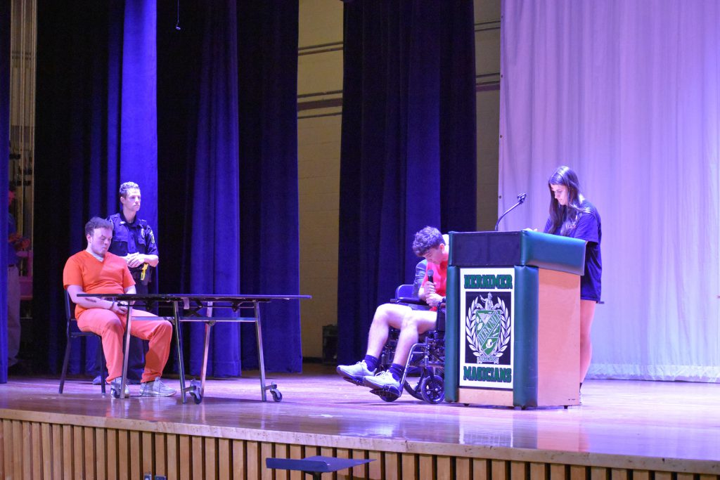 Students and police officer on stage for mock trial