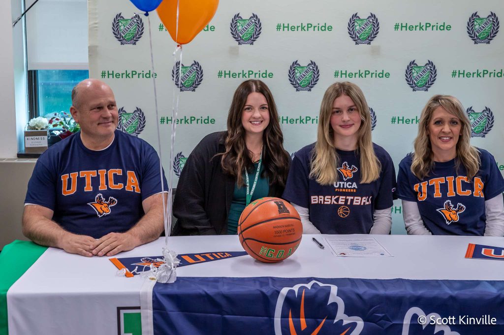 Madison Marusic and three others at her Utica University signing with a Utica University banner on the table