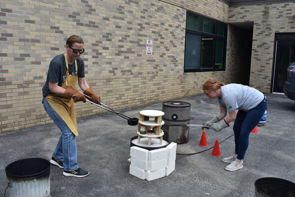 Art teachers removing ceramics from kiln shelves