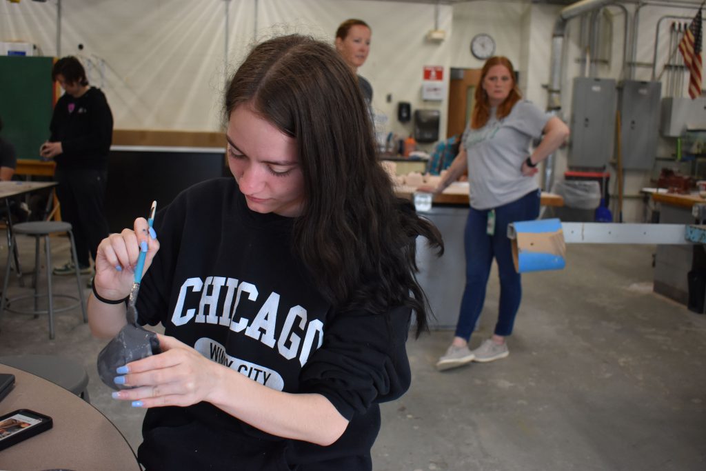 Student brushing glaze on a ceramics piece