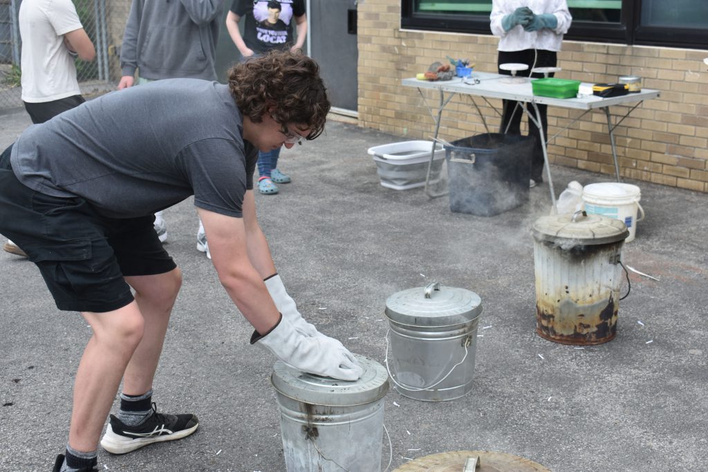 Students puts a lid on a can during Raku firing workshop