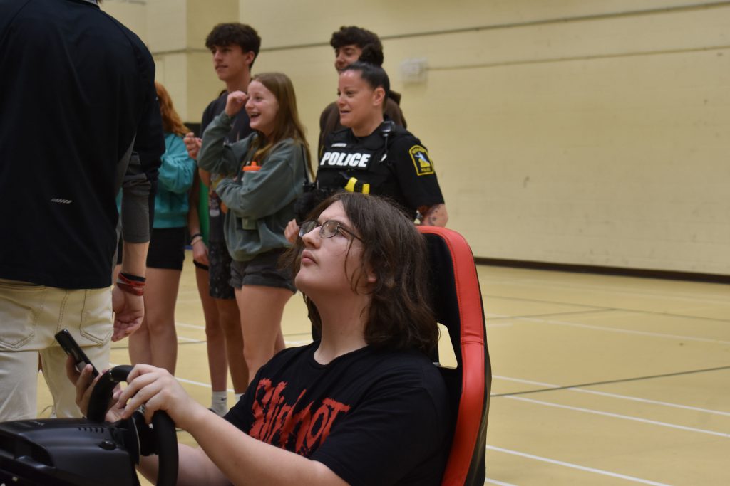 Student driving Save a Life Tour challenge as students and SRO look on
