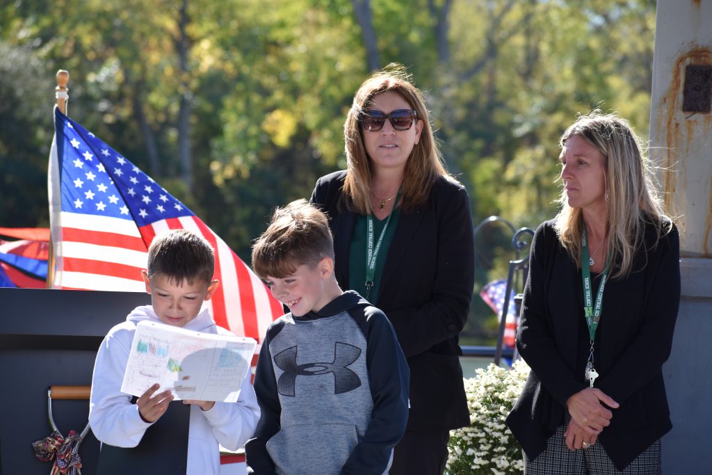 Fourth graders presenting at event as principal and superintendent look on