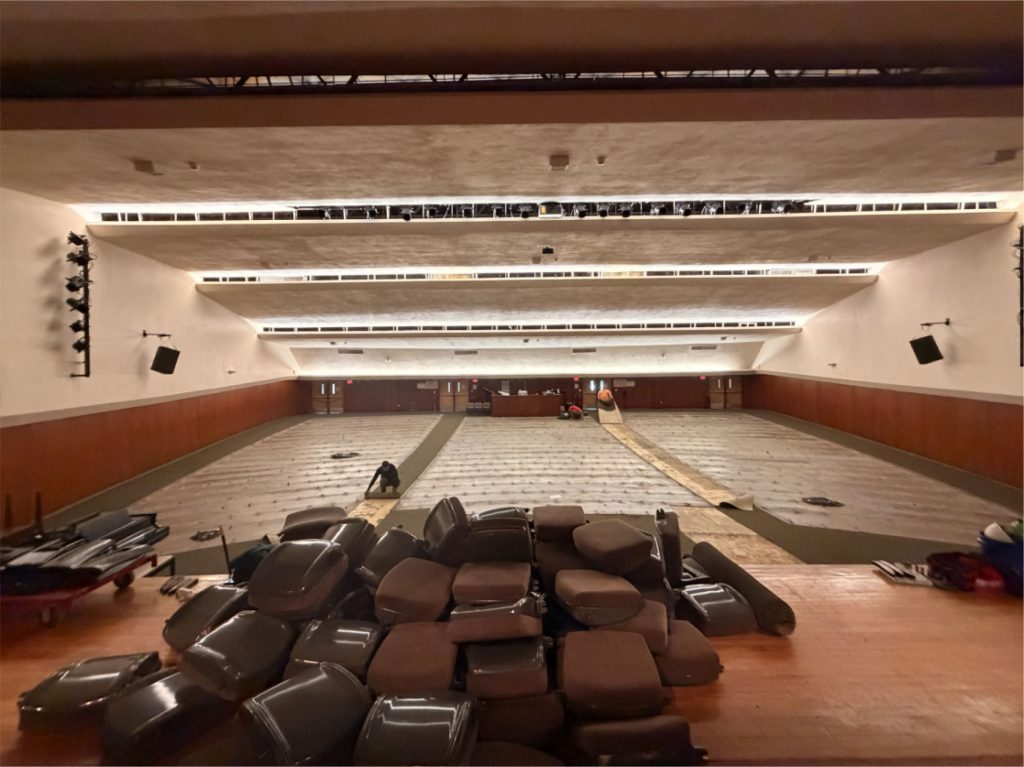 Auditorium under renovation with ripped-out seats stacked on the stage