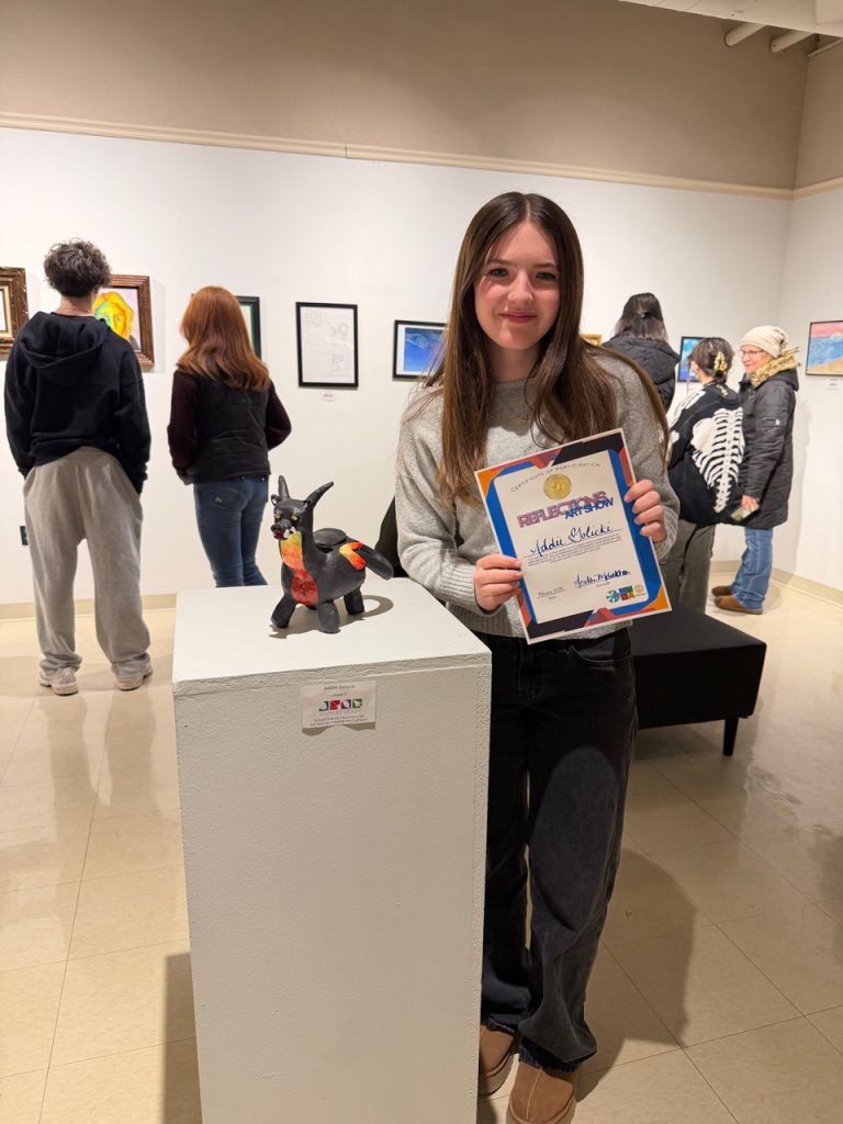 Herkimer student posing with artwork in art exhibit