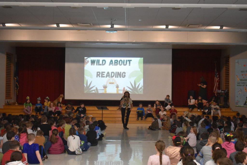 Library Media Specialist Jennifer Olds posing walking through crowd of students during assembly
